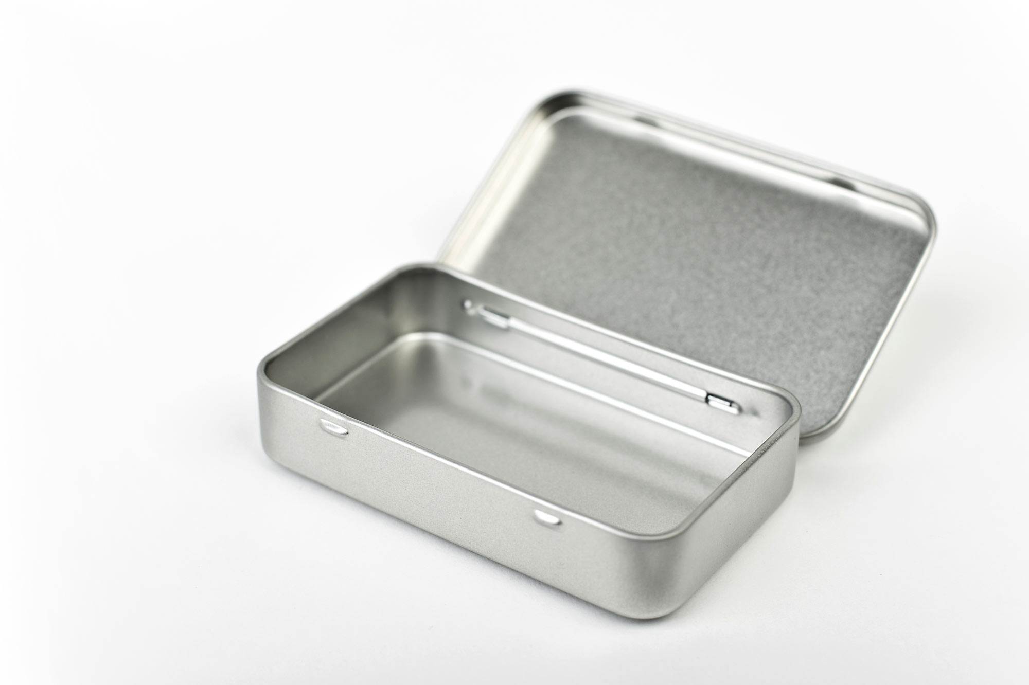 Geöffnete, flache Pocketdose aus silberfarbenem Metall mit Scharnierdeckel, rechteckig, fotografiert auf weißem Hintergrund.