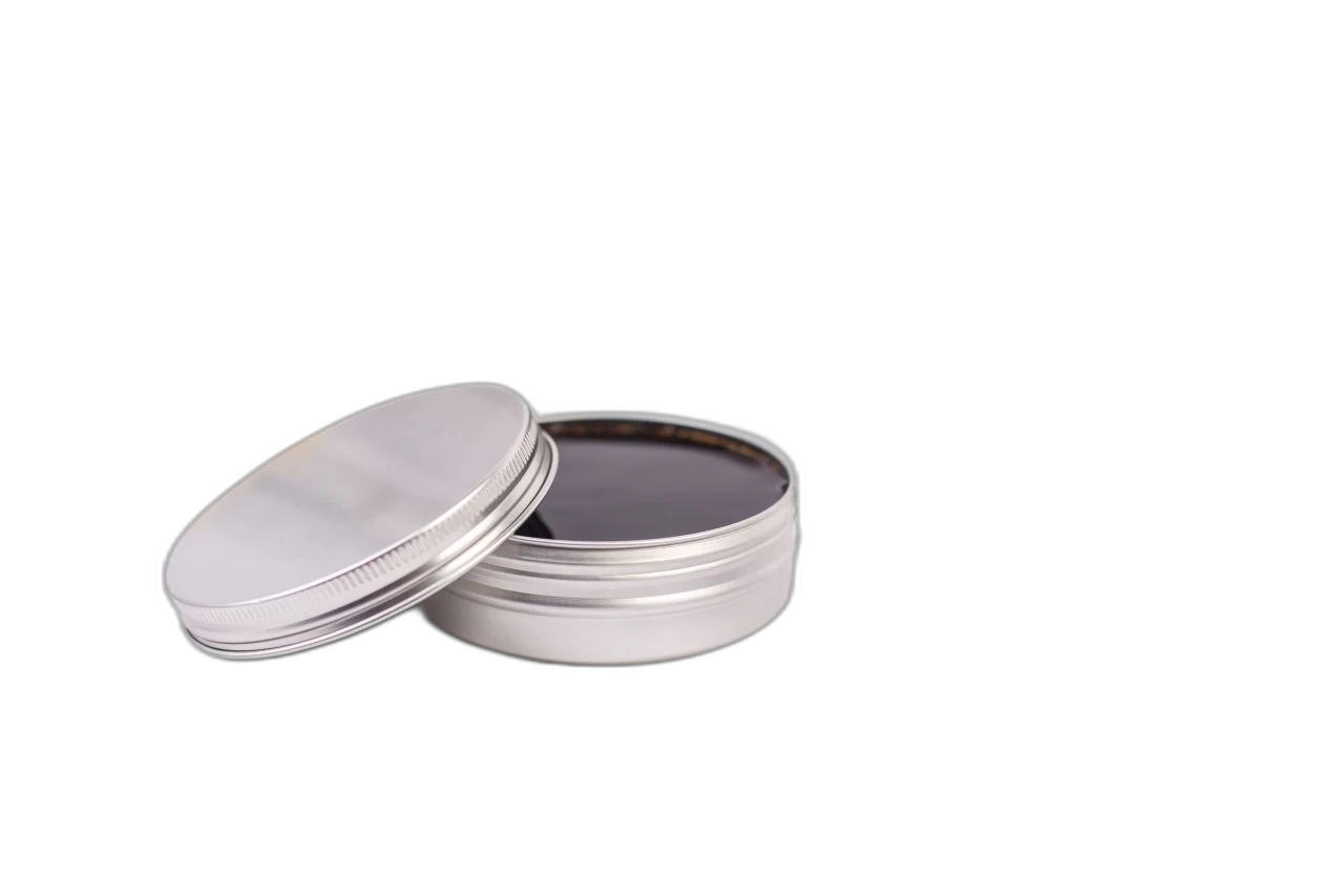 Geöffnete silberne Aluminiumdose mit 125 ml Fassungsvermögen, befüllt mit einer dunklen, möglicherweise öligen Substanz. Der Deckel ist leicht angelehnt und der Hintergrund ist weiß.