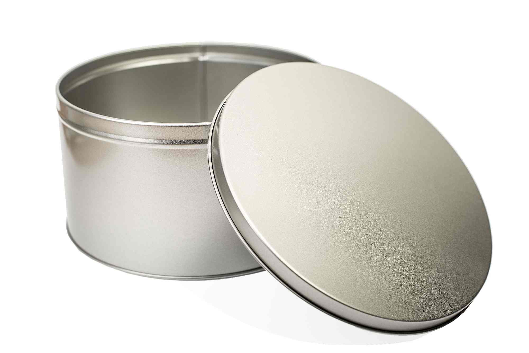 Geöffnete runde Geschenkdose aus silberfarbenem Metall mit abgenommenem Deckel, stehend auf weißem Hintergrund.
